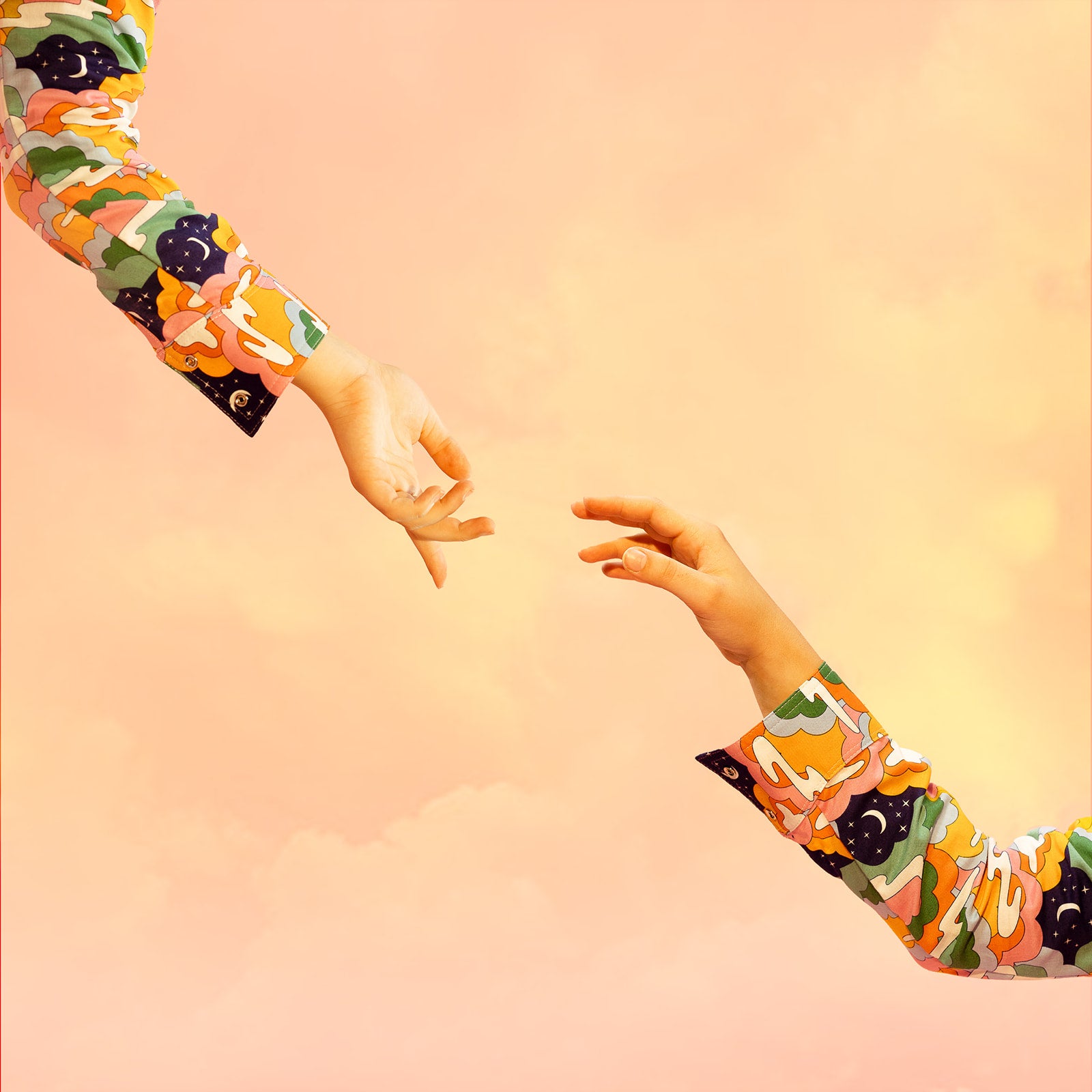 Two hands, wearing colorful cloud-printed shirts, are reaching towards each other.